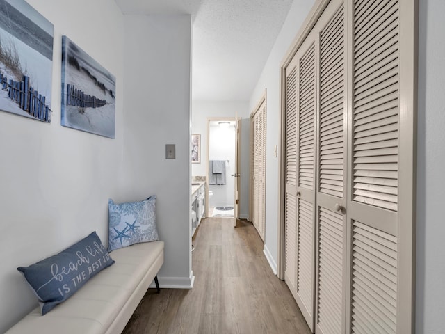 hallway with a textured ceiling and light wood-type flooring