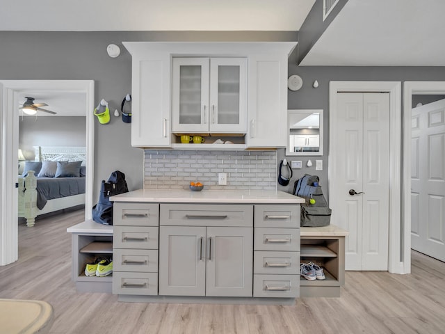 kitchen with ceiling fan, backsplash, and light hardwood / wood-style flooring