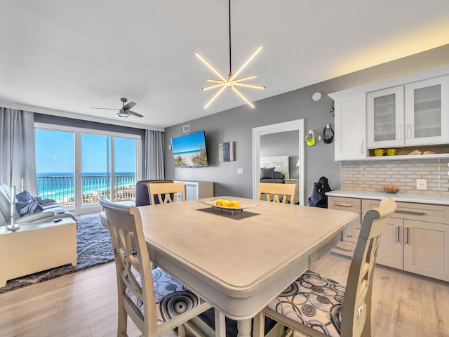 dining space with ceiling fan with notable chandelier and light hardwood / wood-style floors