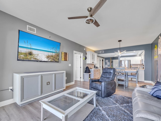 living room with wood-type flooring and ceiling fan with notable chandelier