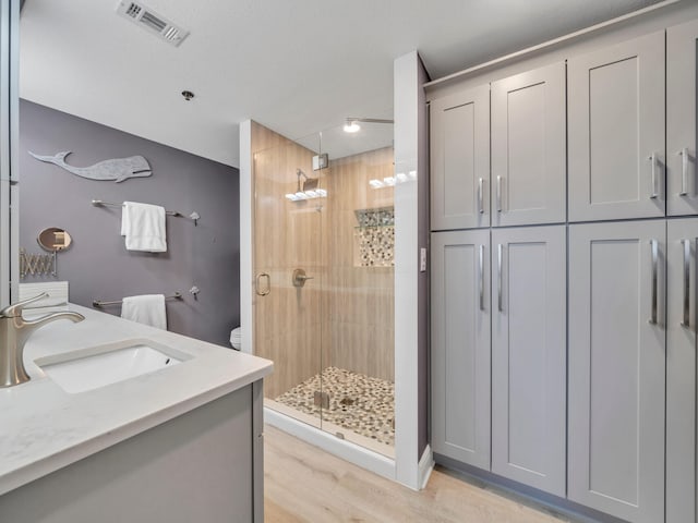 bathroom featuring hardwood / wood-style flooring, vanity, toilet, and a shower with shower door