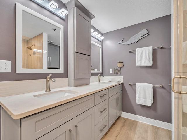 bathroom featuring hardwood / wood-style flooring, vanity, a shower with shower door, and a textured ceiling