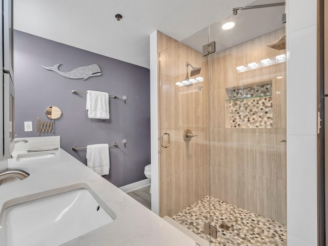 bathroom with hardwood / wood-style floors, vanity, toilet, and a shower with door