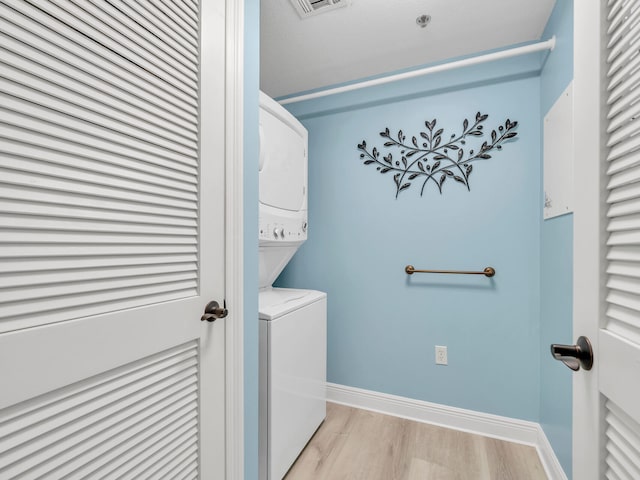 laundry room with light hardwood / wood-style flooring and stacked washer / dryer