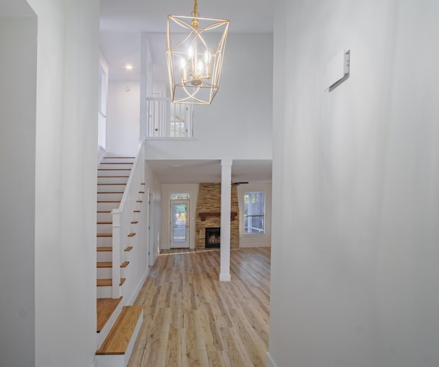 foyer entrance with a fireplace, light hardwood / wood-style floors, and a chandelier