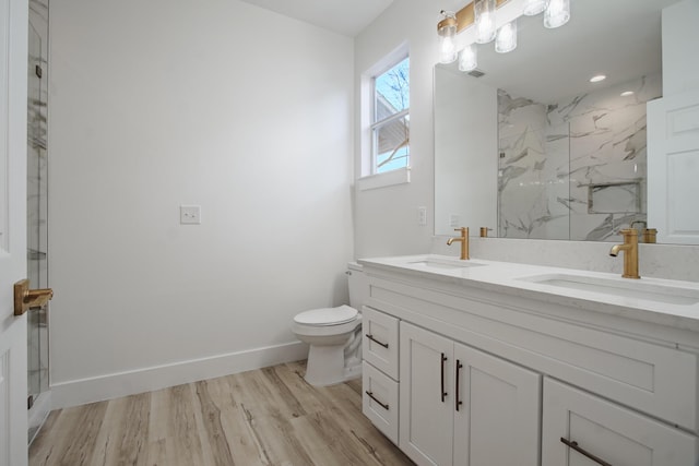 bathroom featuring tiled shower, wood-type flooring, vanity, and toilet