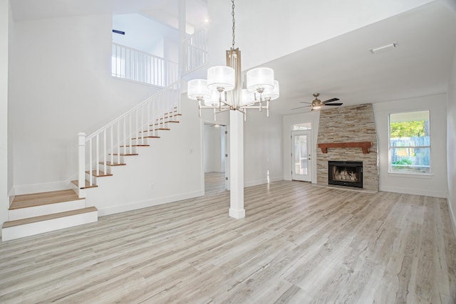 unfurnished living room featuring a fireplace, ceiling fan with notable chandelier, and light hardwood / wood-style flooring