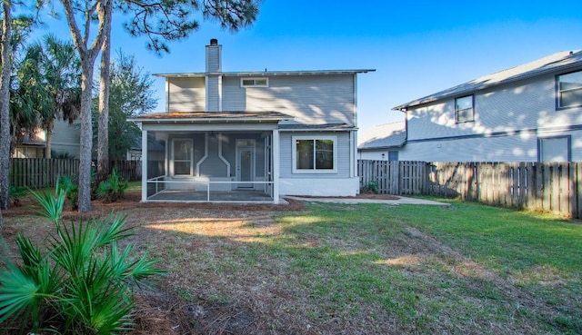 back of property with a sunroom and a lawn