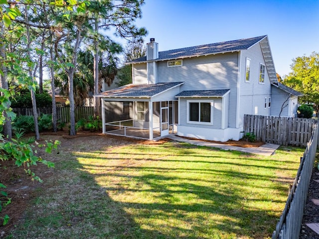 rear view of house with a lawn and a sunroom