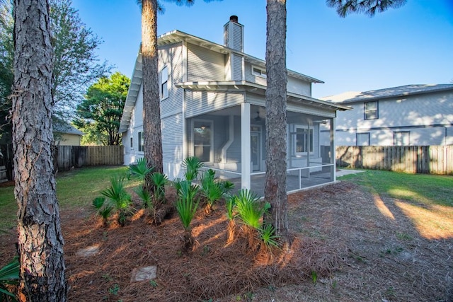 back of house with a lawn and a sunroom