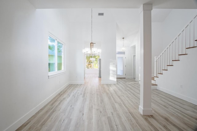 unfurnished living room with a chandelier and light hardwood / wood-style floors