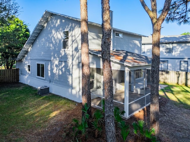 back of house with a sunroom, a yard, and central AC