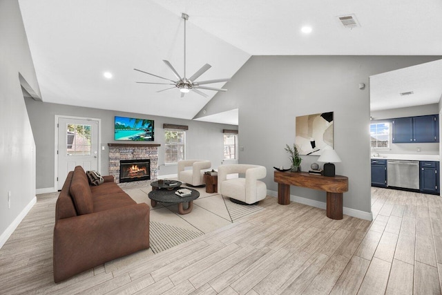 living room with a fireplace, light hardwood / wood-style floors, high vaulted ceiling, and ceiling fan