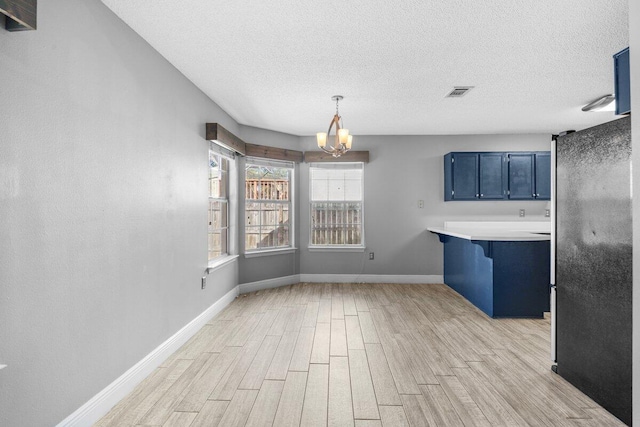 interior space with light hardwood / wood-style floors, a textured ceiling, and a notable chandelier