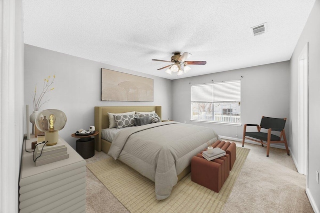 bedroom with a textured ceiling, light colored carpet, and ceiling fan