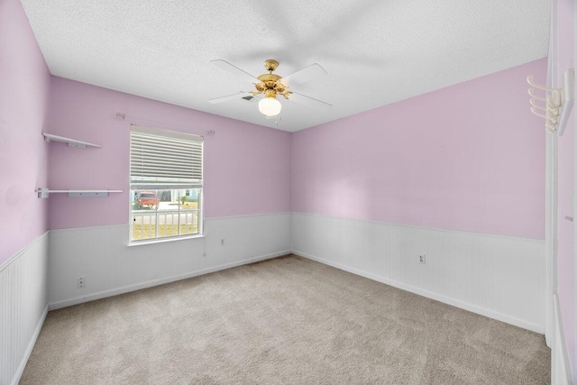 carpeted spare room featuring ceiling fan and a textured ceiling