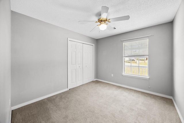 unfurnished bedroom with ceiling fan, a closet, carpet, and a textured ceiling