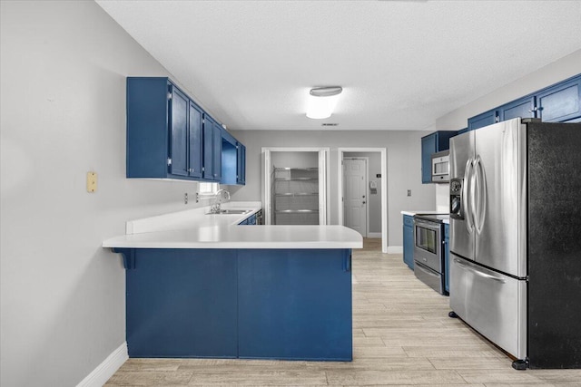 439 Northview Ln, Crestview, FL 32536 - kitchen featuring a peninsula, blue cabinetry, appliances with stainless steel finishes, and light wood finished floors