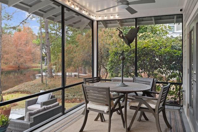 unfurnished sunroom with rail lighting, a water view, and ceiling fan