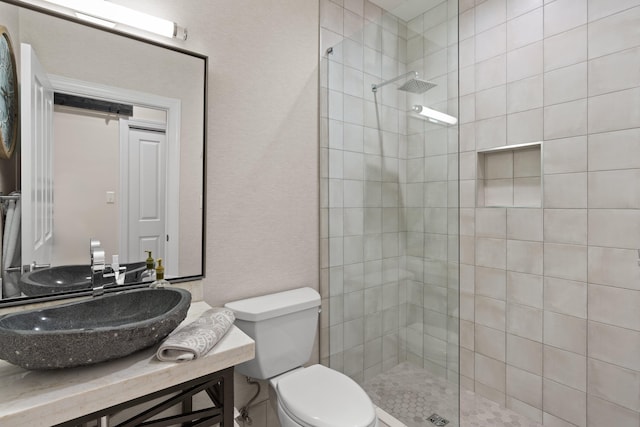 bathroom with vanity, toilet, and a tile shower