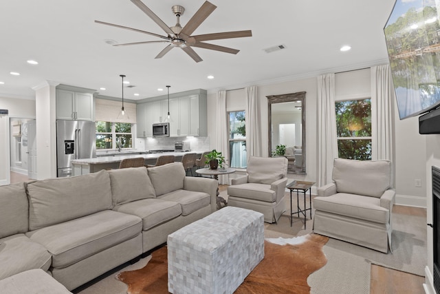 living room with ceiling fan and ornamental molding