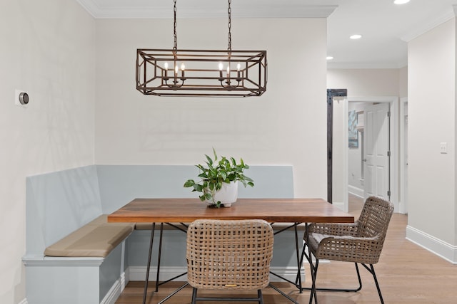 dining area with crown molding, breakfast area, a chandelier, and hardwood / wood-style flooring