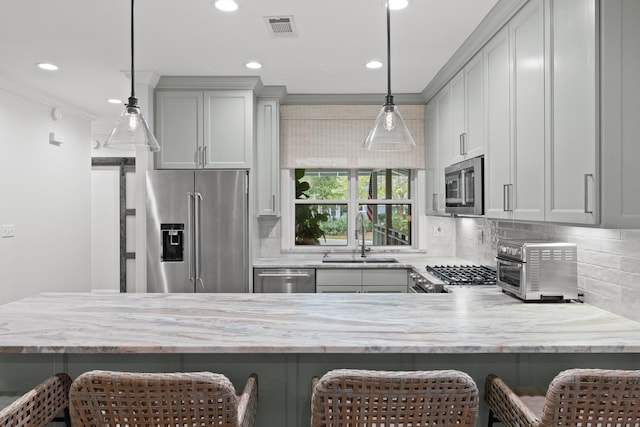 kitchen with gray cabinets, a kitchen bar, sink, and appliances with stainless steel finishes