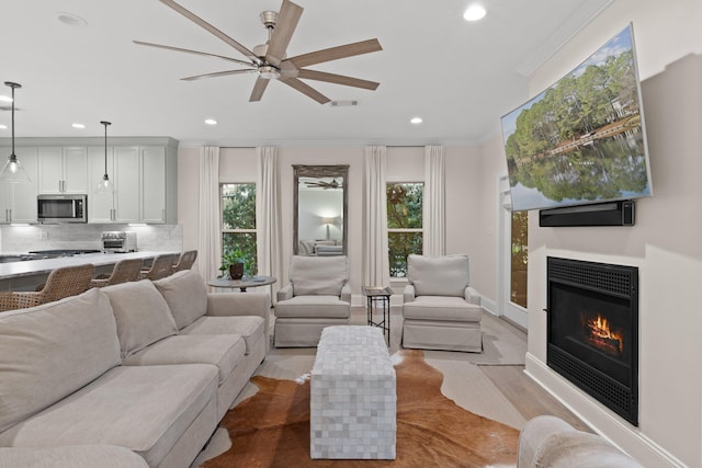 living room with ceiling fan, crown molding, and a wealth of natural light