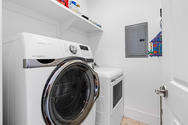 washroom with light tile patterned floors, electric panel, and washing machine and clothes dryer