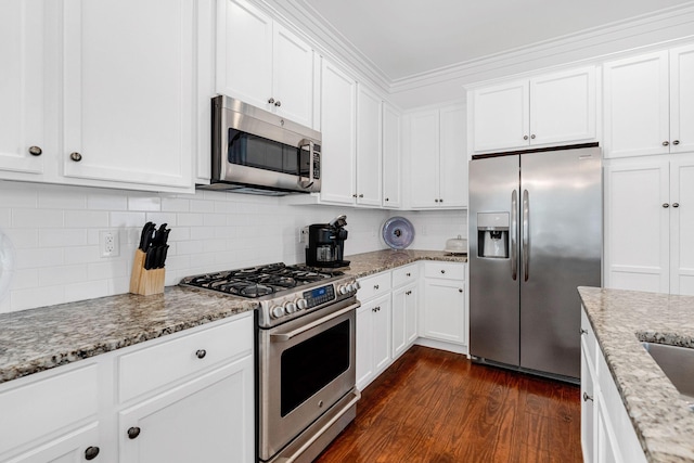 kitchen featuring stainless steel appliances, light stone counters, dark hardwood / wood-style floors, white cabinets, and ornamental molding