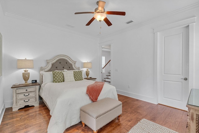 bedroom featuring hardwood / wood-style flooring, ceiling fan, and ornamental molding