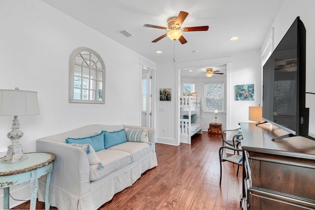 living room featuring ceiling fan and dark hardwood / wood-style floors