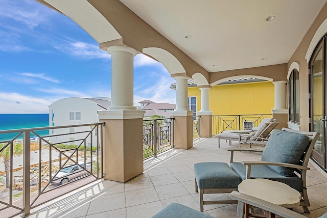 view of patio with a water view, a beach view, and a balcony