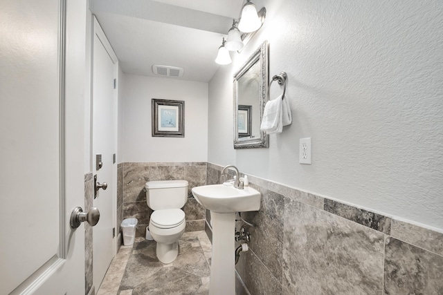 bathroom featuring sink, tile walls, and toilet