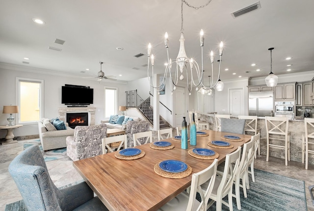 dining space with ceiling fan with notable chandelier and crown molding