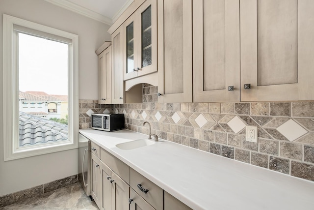 kitchen with decorative backsplash, washer / dryer, ornamental molding, and sink