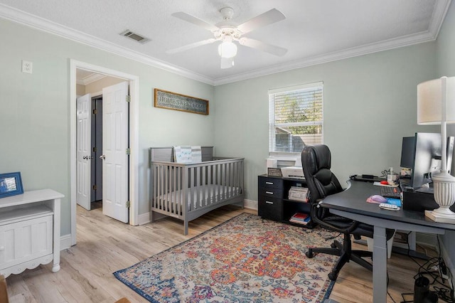 bedroom featuring crown molding, ceiling fan, light wood-type flooring, a textured ceiling, and a crib