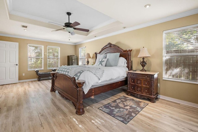 bedroom with ceiling fan, light hardwood / wood-style floors, a raised ceiling, and crown molding