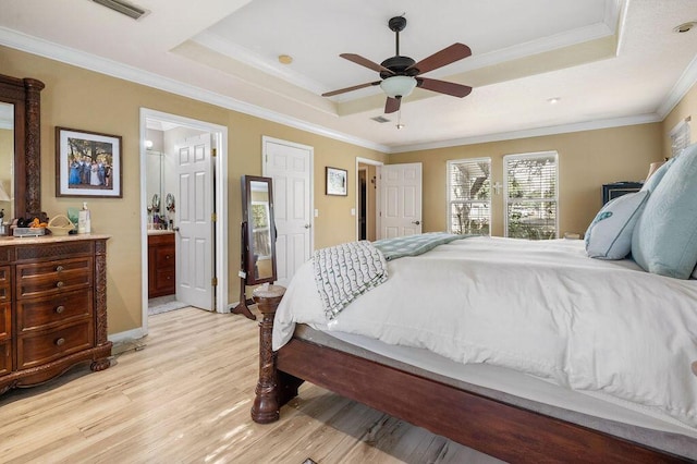 bedroom with a raised ceiling, light hardwood / wood-style floors, ensuite bath, and ceiling fan