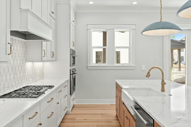 kitchen featuring light stone countertops, plenty of natural light, white cabinets, and decorative light fixtures