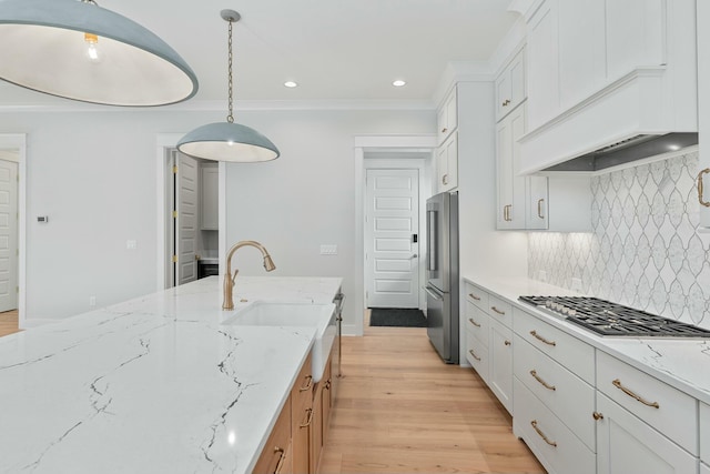 kitchen featuring white cabinets, light hardwood / wood-style floors, hanging light fixtures, and stainless steel appliances