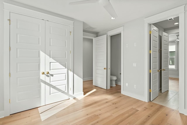 unfurnished bedroom featuring ceiling fan, a closet, ensuite bathroom, and light hardwood / wood-style floors