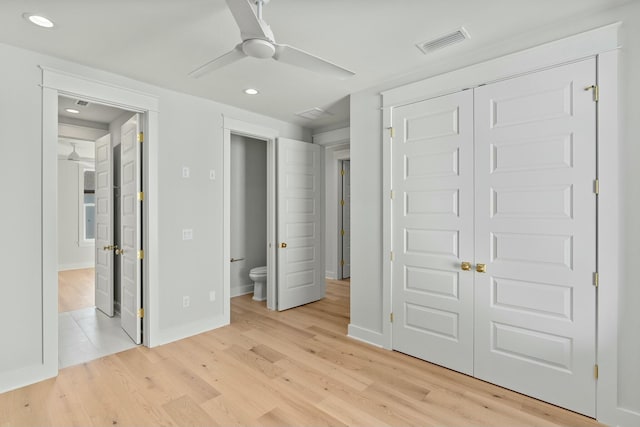 unfurnished bedroom featuring ceiling fan, light hardwood / wood-style floors, ensuite bath, and a closet