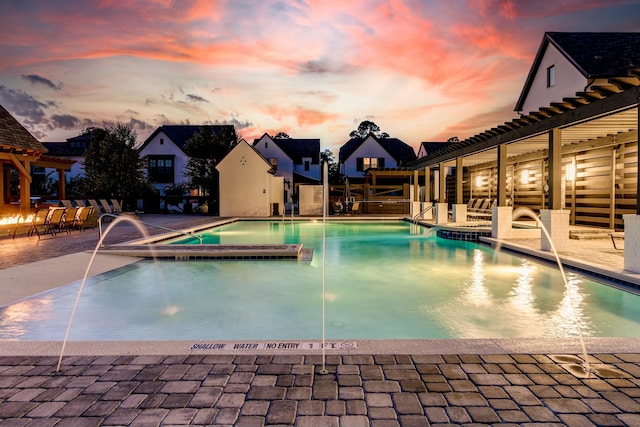 pool at dusk with a patio area, a pergola, and a jacuzzi