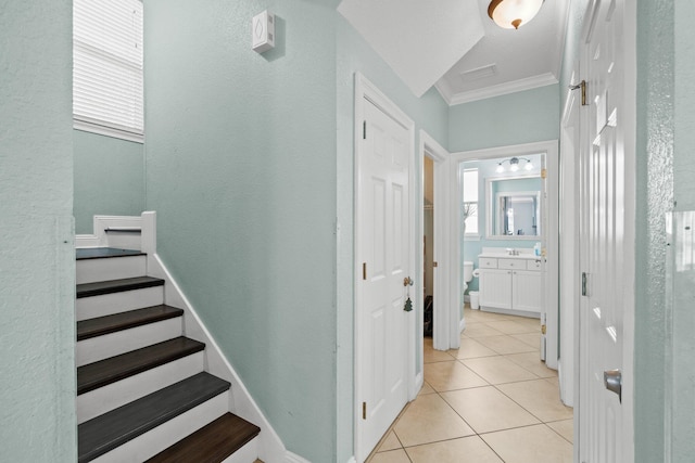 stairway with tile patterned floors and crown molding