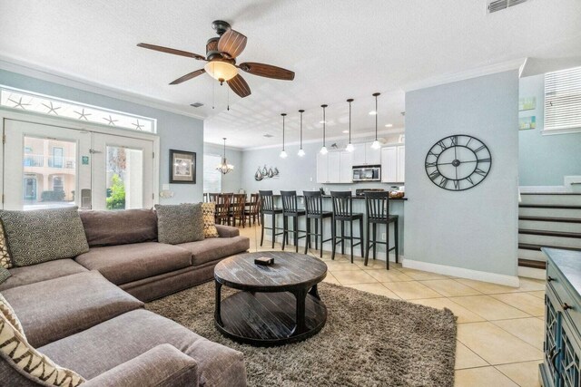 living room with ceiling fan with notable chandelier, light tile patterned floors, a textured ceiling, and crown molding