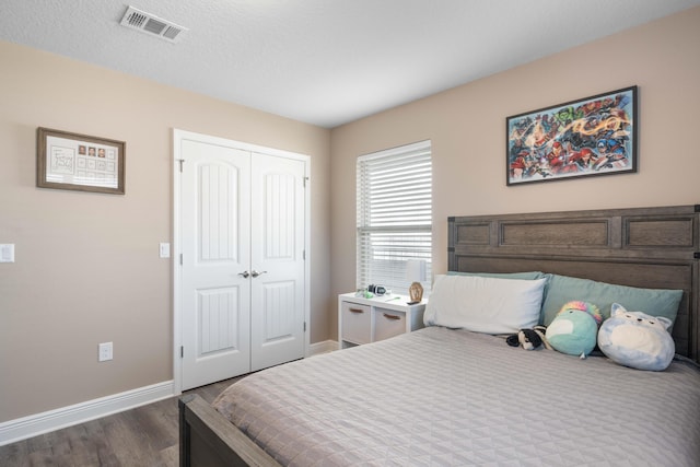 bedroom featuring a closet, dark hardwood / wood-style flooring, and a textured ceiling