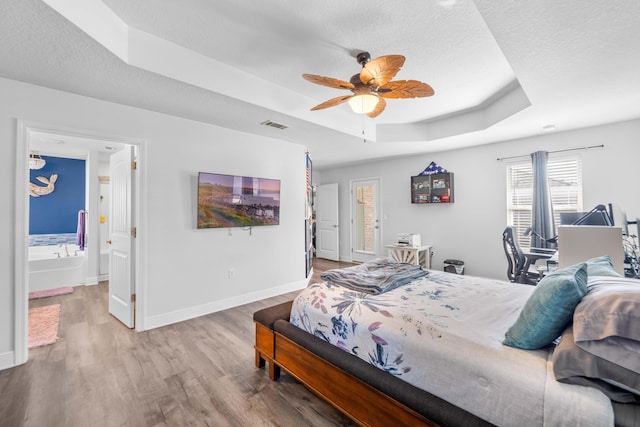 bedroom featuring a textured ceiling, light wood-type flooring, a raised ceiling, and ceiling fan