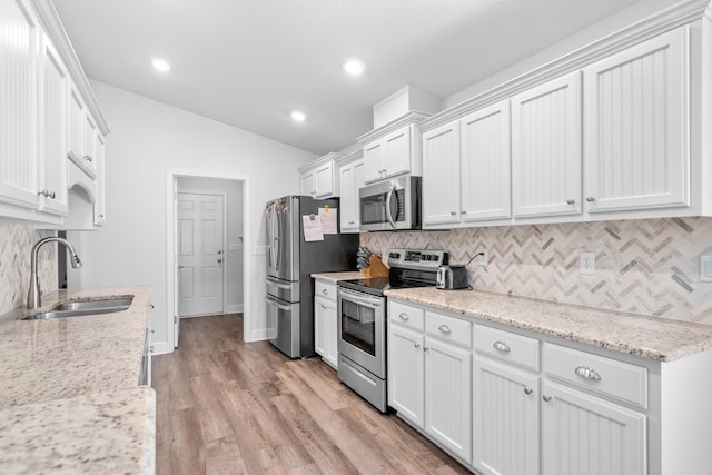 kitchen featuring appliances with stainless steel finishes, light hardwood / wood-style floors, white cabinetry, and light stone counters