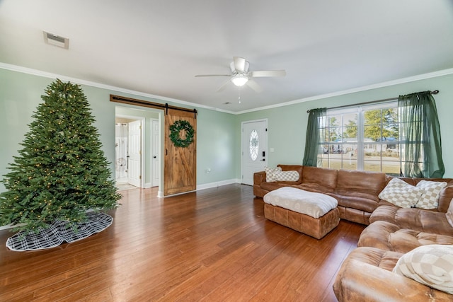 living room featuring hardwood / wood-style floors, a barn door, ceiling fan, and ornamental molding